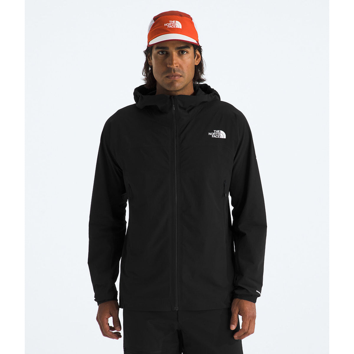 A man wearing a black The North Face zip-up hooded jacket and an orange and white The North Face cap, standing against a light gray studio background. - The North Face Summit Series Off Width Jacket (Men's) - TNF Black
