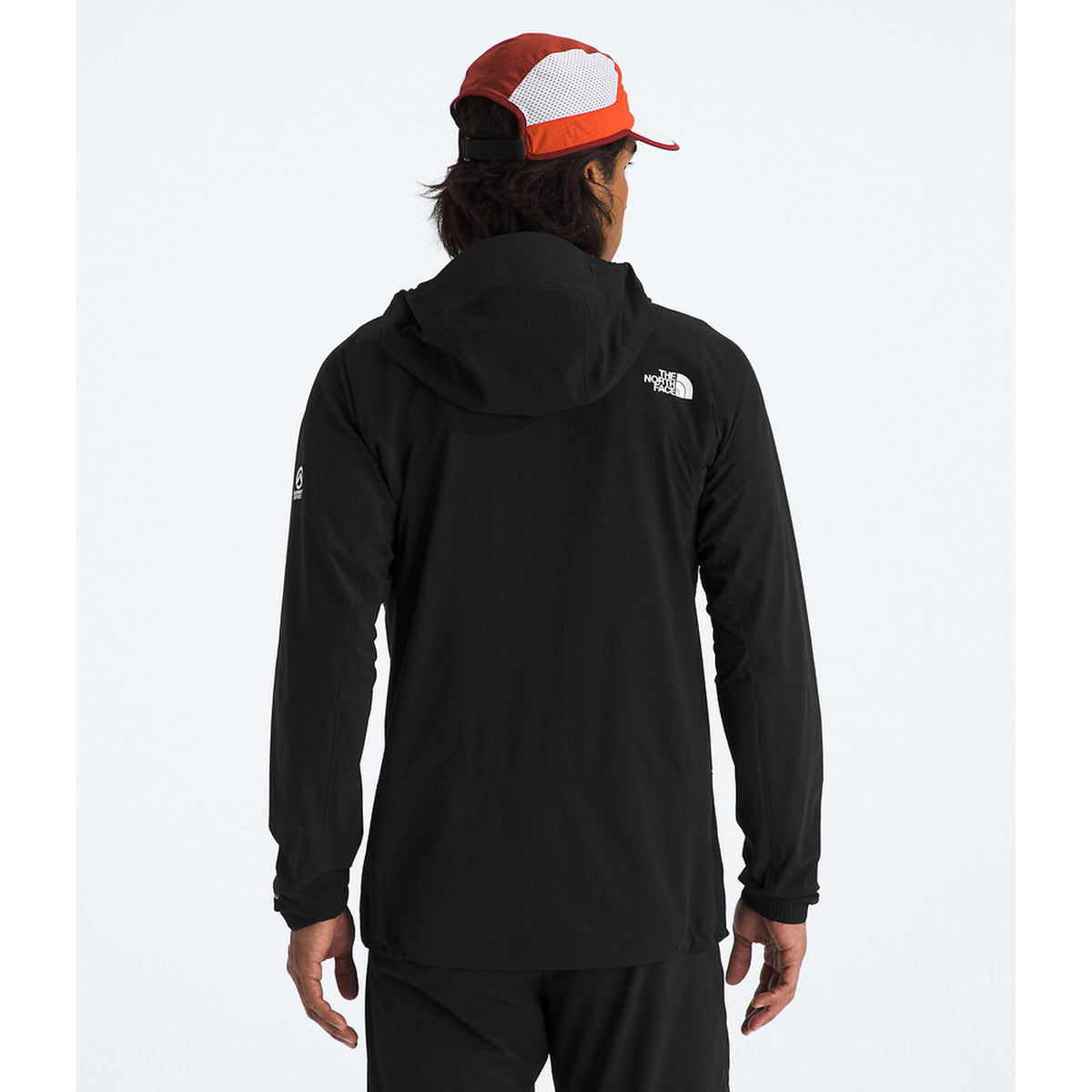 Person wearing a black hoodie with a logo on the back, standing against a white background - The North Face Summit Series Off Width Jacket (Men's) - TNF Black