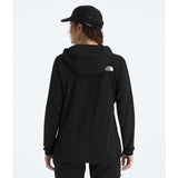 A woman viewed from behind wearing a black hooded jacket with a small white The North Face logo on the back, along with a black cap, against a light gray studio background. - The North Face Summit Series Off Width Jacket (Women's) - TNF Black