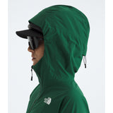A side profile of a person wearing a green hooded jacket by The North Face, a black cap, and dark sunglasses, against a light gray background. - The North Face Summit Series Off Width Jacket (Women's) - Evergreen