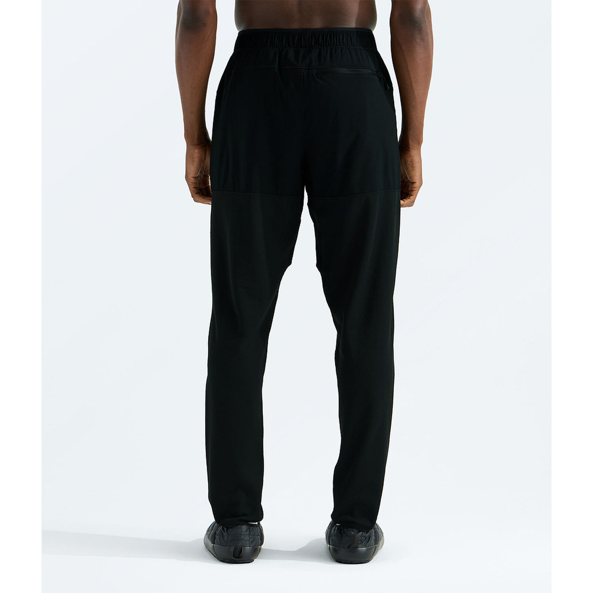 Black athletic pants with a drawstring waist, shown from the back on a model against a light gray studio background. - The North Face Summit FUTUREFLEECE Pants (Men's) - TNF Black