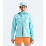 A woman modeling a light blue hooded jacket and matching bucket hat from The North Face, paired with orange shorts, against a plain white studio background. - The North Face Summit FUTURELIGHT Superior Jacket-Graphic (Women's) - Canal Blue