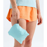 A close-up of a person wearing bright orange perforated athletic shorts and a light blue top, holding a matching light blue drawstring pouch. - The North Face Summit FUTURELIGHT Superior Jacket-Graphic (Women's) - Canal Blue