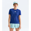 A woman modeling a royal blue short-sleeve athletic t-shirt by The North Face, paired with light blue shorts and a matching light blue cap, against a plain light gray studio background. - The North Face Summit High Trail Short Sleeve-Graphic (Women's) - Bold Blue