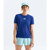 A woman modeling a royal blue short-sleeve athletic t-shirt by The North Face, paired with light blue shorts and a matching light blue cap, against a plain light gray studio background. - The North Face Summit High Trail Short Sleeve-Graphic (Women's) - Bold Blue