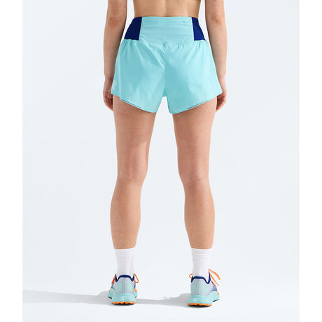 A person shown from the back wearing light aqua athletic shorts with dark navy side panels, white socks, and matching light aqua running shoes against a clean white studio background. - The North Face Summit Pacesetter Short-Graphic (Women's) - Canal Blue