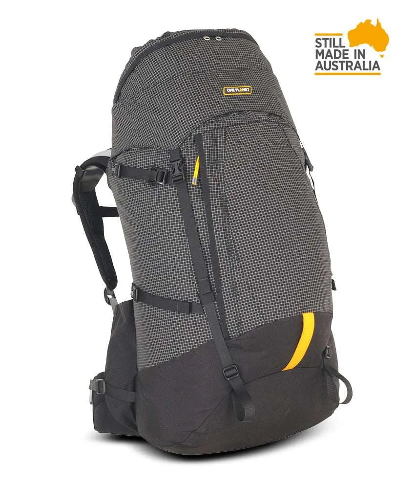 A dark gray and black technical hiking backpack with yellow accents, shown on a white background with a 'Still Made in Australia' badge in the top right corner. - One Planet Tussock 60L Pack - Black