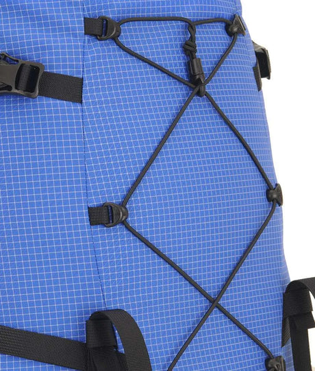 Close-up of a blue grid-patterned backpack with black compression straps and plastic buckles, showing the side and front lacing details against a white background. - One Planet Extrovert 55 Pack - Blue