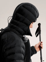 Person wearing a black puffer jacket with a hood, holding ski poles against a light background - Arc'teryx Cerium Hoody (Men's) - Black
