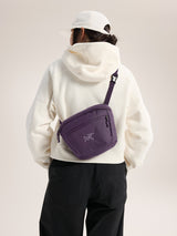 Person wearing a white hoodie and black pants with a purple bag over one shoulder on a plain background - Arc'teryx Mantis 2 Waist Pack - Moondrop