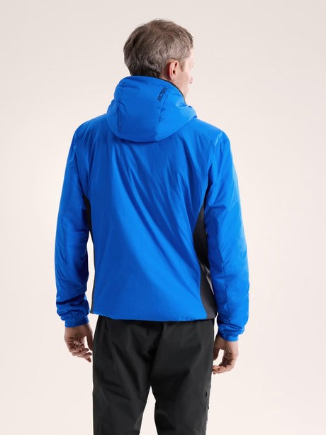 Person wearing a blue jacket with a hood on a beige background - Arc'teryx Atom Hoody (Men's) - Fluidity/Black Sapphire