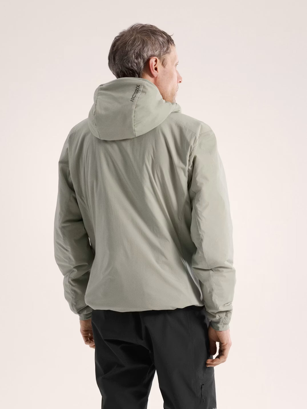 Person wearing a green jacket on a beige background - Arc'teryx Atom Hoody (Men's) - Habitat