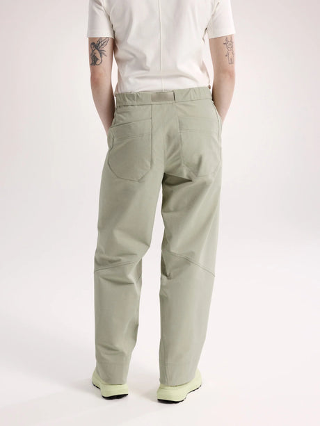 A person shown from the back wearing light sage green cargo pants, a white short-sleeve top, and light green sneakers against a plain light gray studio background. - Arc'teryx Nia Pants (Women's) - Habitat