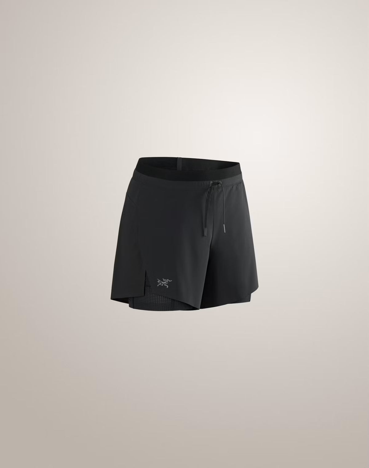 Black athletic shorts with a drawstring waist and a small Arc'teryx logo near the hem, shown against a light beige studio background. - Arc'teryx Norvan Shorts 5" 2-in-1 (Women's) - Black