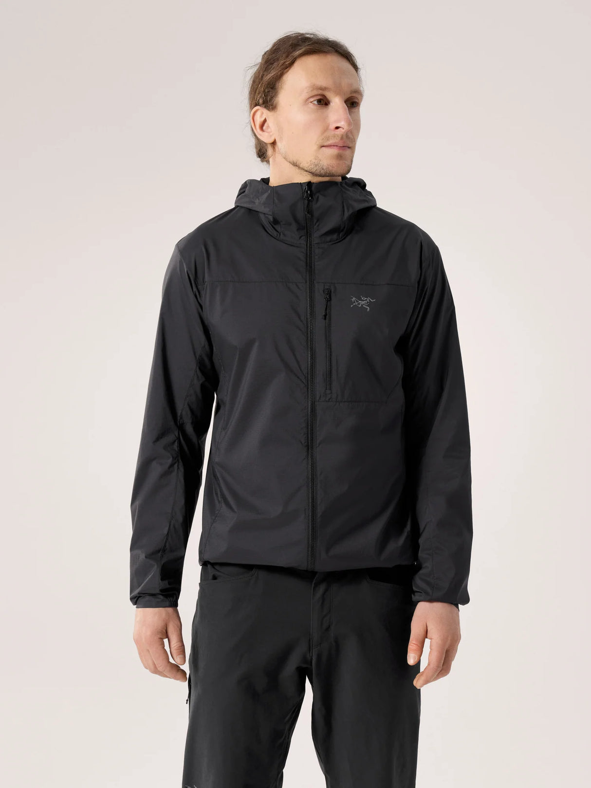 Man wearing a black jacket with a hood on a light gray background - Arc'teryx Squamish Hoody (Men's) - Black