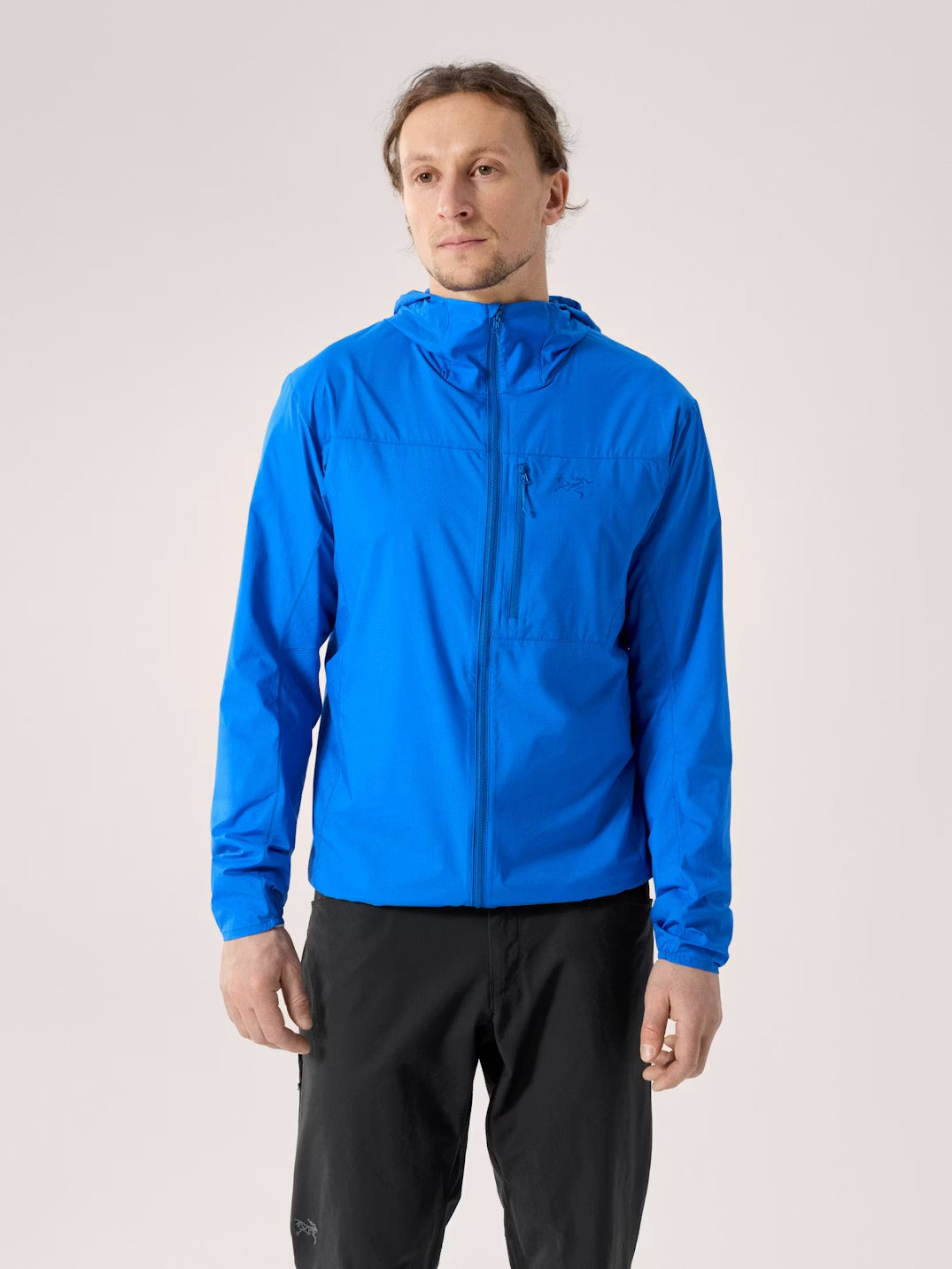 Man wearing a blue jacket and black pants on a light gray background - Arc'teryx Squamish Hoody (Men's) - Fluidity