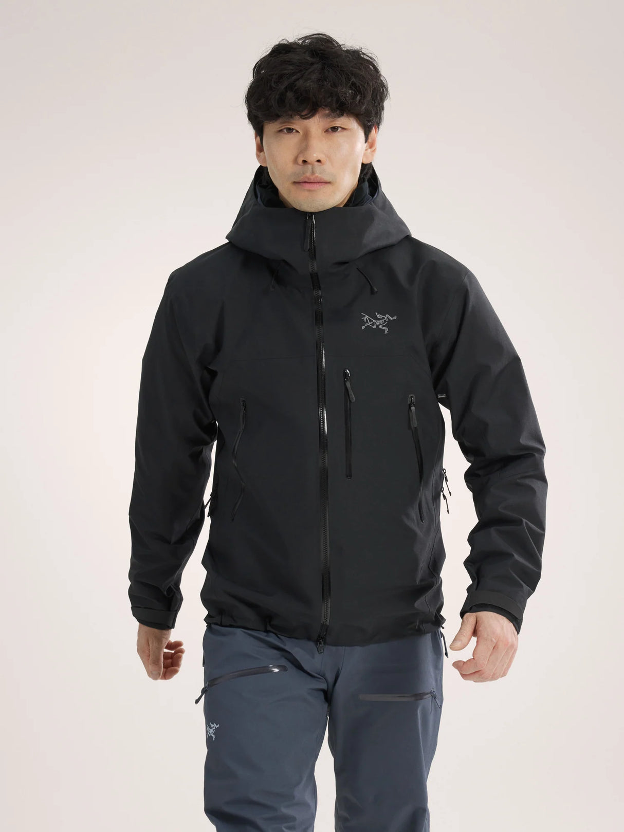 Person wearing a black jacket with a brand logo on a light gray background - Arc'teryx Beta SV Jacket (Men's) - Black