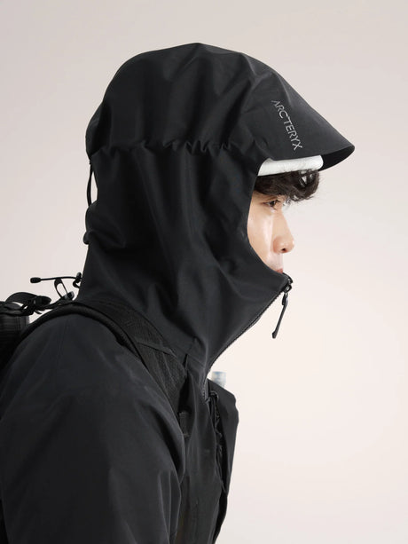 Person wearing a black jacket with a hood, featuring a brand logo, on a plain background. - Arc'teryx Beta SV Jacket (Men's) - Black