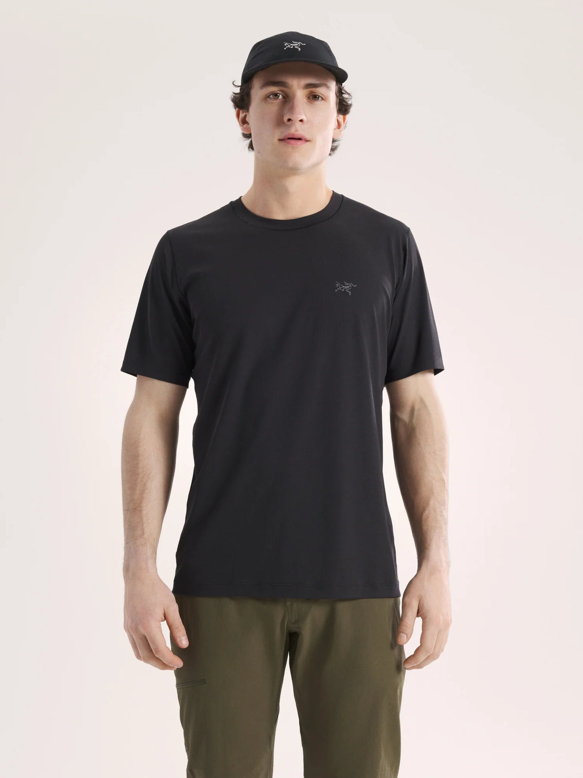 Man wearing a black t-shirt and cap on a light pink background - Arc'teryx Cormac Crew Neck Shirt Short Sleeve (Men's) - Black