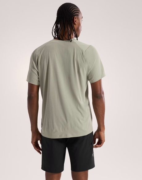 Person wearing a light green t-shirt and black shorts on a plain background - Arc'teryx Cormac Crew Neck Shirt Short Sleeve (Men's) - Habitat