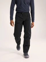 A model wearing black technical cargo pants, a navy long-sleeve shirt, and gray athletic shoes, shown from the chest down against a light gray studio background. - Arc'teryx Beta Pants (Men's) - Black