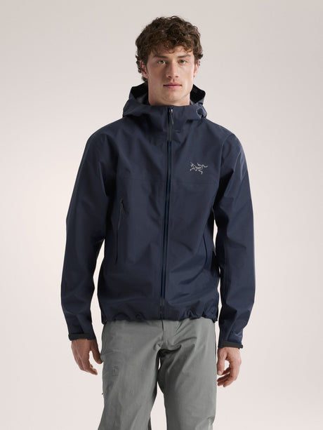 Man wearing a navy blue jacket with a brand logo on a light gray background - Arc'teryx Beta Jacket (Men's) - Black Sapphire