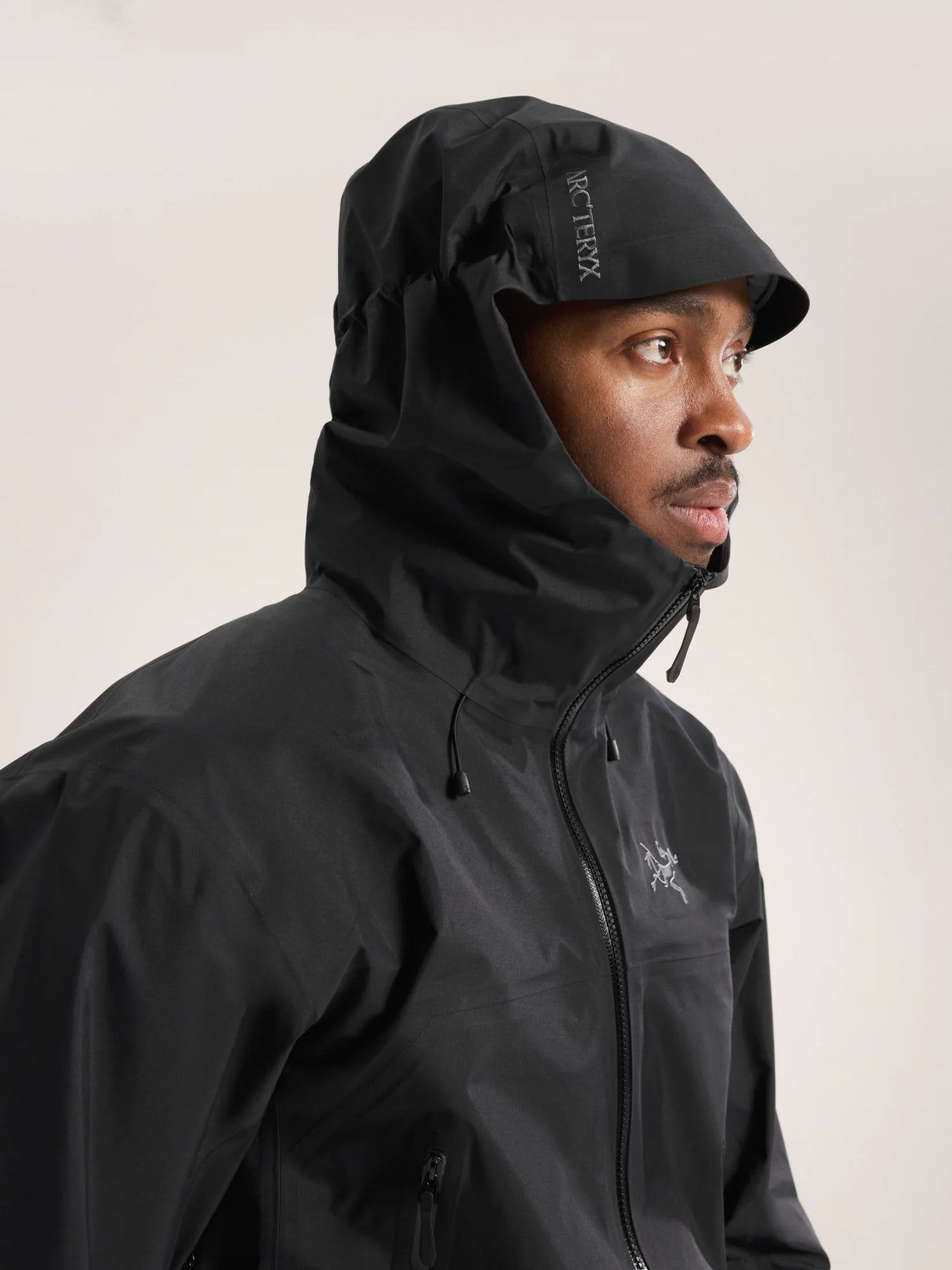 Person wearing a black jacket with a hood on a light gray background - Arc'teryx Beta SL Jacket (Men's) - Black
