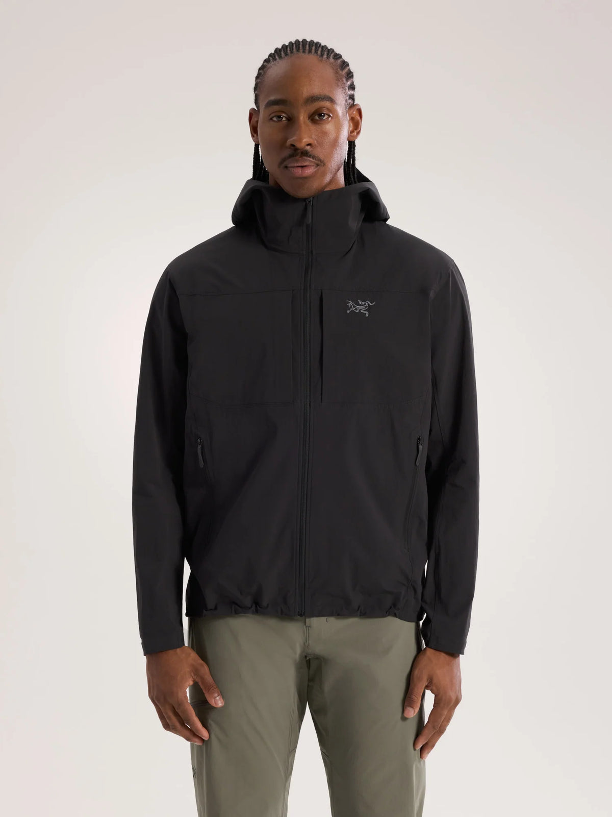A man wearing a black Arc'teryx hooded jacket and olive green pants, standing against a light gray studio background. - Arc'teryx Gamma Lightweight Hoody (Men's) - Black
