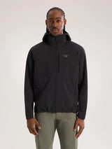 A man wearing a black Arc'teryx hooded jacket and olive green pants, standing against a light gray studio background. - Arc'teryx Gamma Lightweight Hoody (Men's) - Black