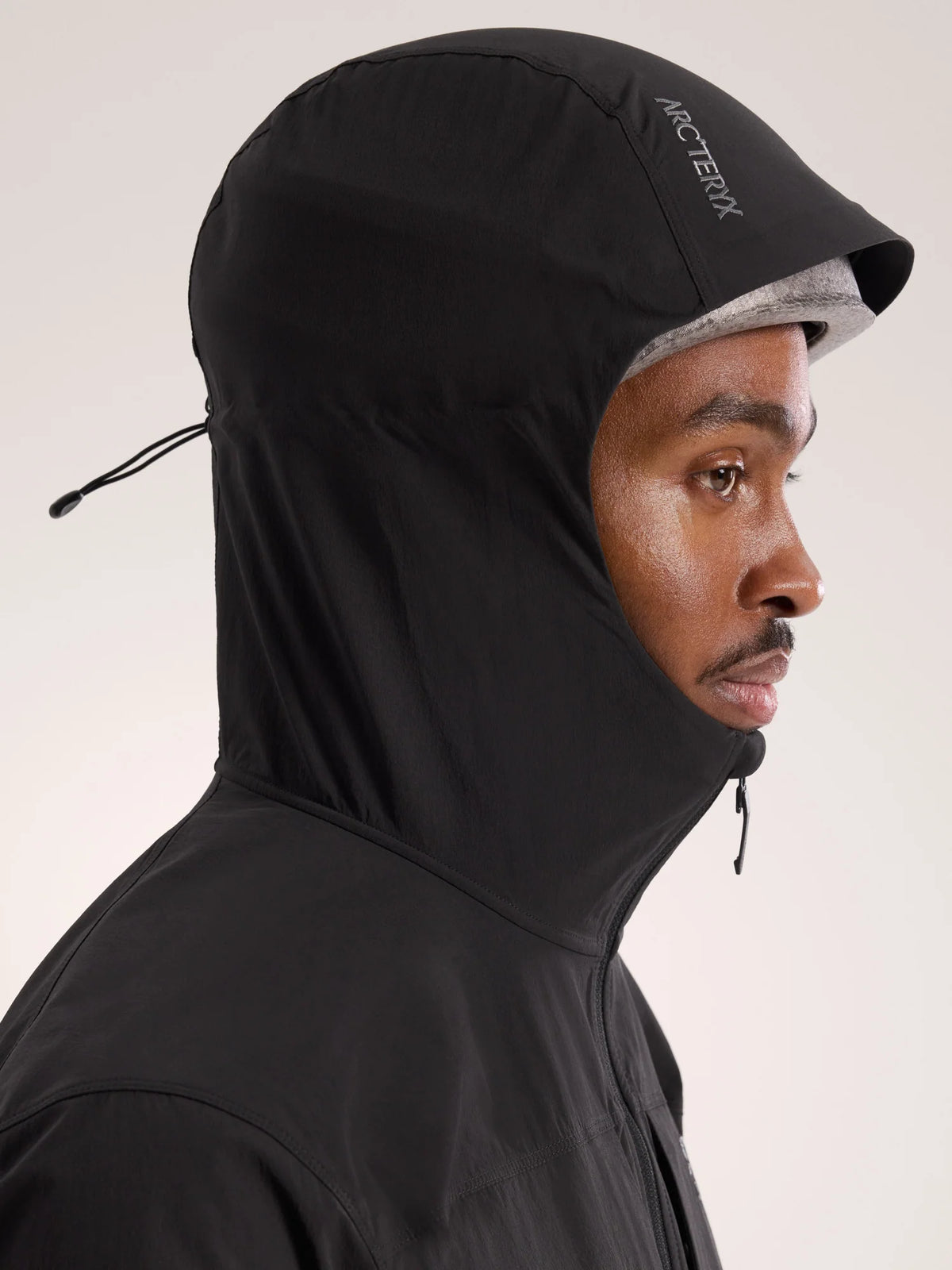 Person wearing a black hooded jacket with 'Arc'teryx' branding on a light background - Arc'teryx Gamma Lightweight Hoody (Men's) - Black