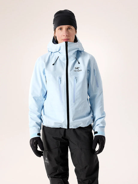 Person wearing a light blue jacket with a brand logo on a plain background - Arc'teryx Alpha SV Jacket (Women's) - Alpine Blue/Black