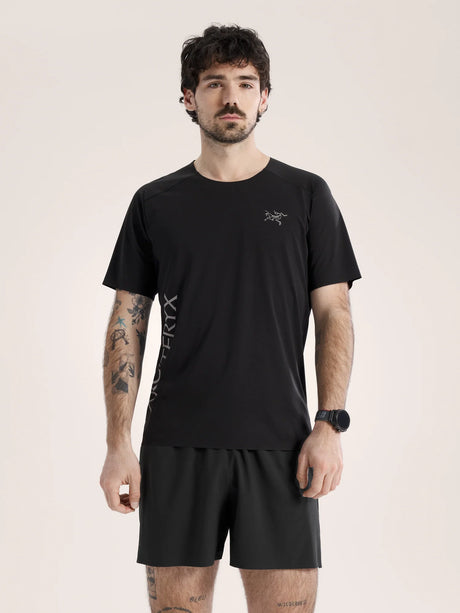Man wearing a black t-shirt and shorts with a logo on a beige background - Arc'teryx Norvan Downword Logo Shirt Short Sleeve (Men's) - Black