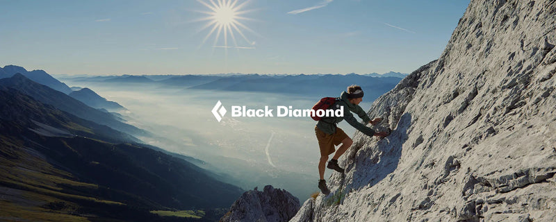 climber in black diamond apparel climbing a mountain and the black diamond logo in white on top of the picture