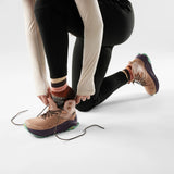 Person adjusting the laces of a brown shoe on a white background - Smartwool Hike Margarita Light Cushion Ankle Socks (Women's) - Chestnut