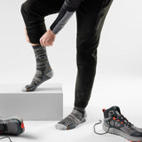 Person wearing black pants and gray patterned socks with hiking shoes on a light gray background - Smartwool Hike Mountain Range Light Cushion Crew Socks (Unisex) - Charcoal/Light Grey