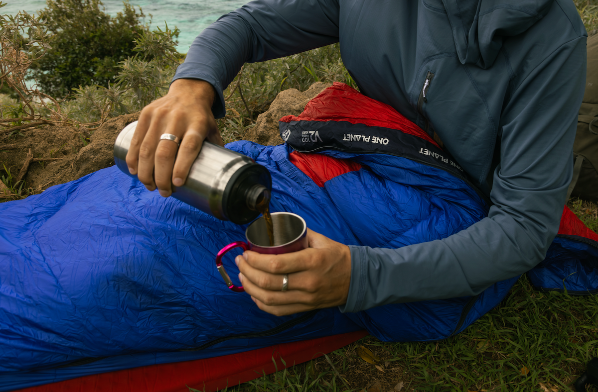 Person camping sitting on a sleeping mat in a one planer sonder sleeping bag