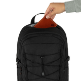 A black backpack shown from the front with a hand inserting a brown leather wallet into the top zipper compartment, against a plain white background. - Fjällräven Skule 28 Backpack - Black