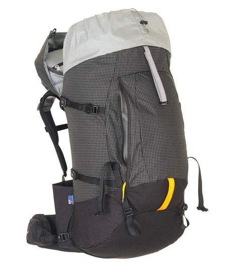 A large technical hiking backpack shown from the side against a plain white background. The backpack features a dark gray and black grid-patterned main body, a light gray top rain cover, black straps and buckles, and a small yellow accent on the lower front pocket. - One Planet Tussock 60L Pack - Black