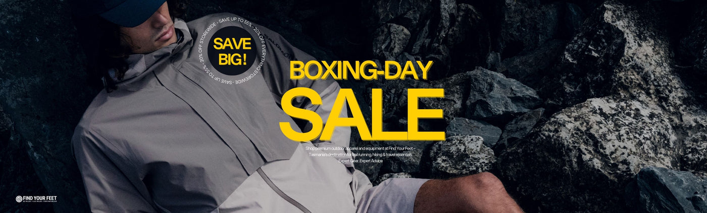 trail runner wearing a gray jacket outside in nature with 'Boxing Day Sale' text overlay and find your feet logo