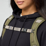 Person wearing a black hoodie with a green backpack on a light gray background - Fjällräven Vardag Foldsack 25 - Green/Clay
