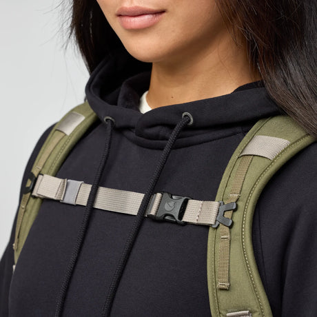 Person wearing a black hoodie with a green backpack on a light gray background - Fjällräven Vardag Foldsack 25 - Green/Clay
