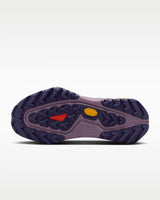 A Nike ACG ZEGAMA ZOOMX trail running shoe in a light lavender and purple colorway, featuring a textured mesh upper, a purple Swoosh, and a purple Vibram outsole, shown from a side profile on a light gray background.