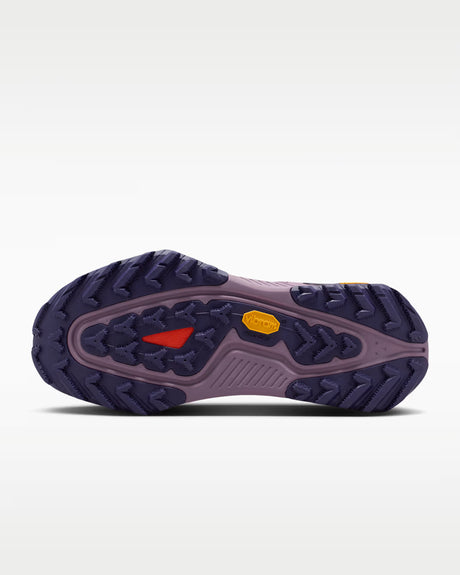 A Nike ACG ZEGAMA ZOOMX trail running shoe in a light lavender and purple colorway, featuring a textured mesh upper, a purple Swoosh, and a purple Vibram outsole, shown from a side profile on a light gray background.