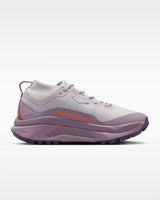 A Nike ACG ZEGAMA ZOOMX trail running shoe in a light lavender and purple colorway, featuring a textured mesh upper, a purple Swoosh, and a purple Vibram outsole, shown from a side profile on a light gray background.