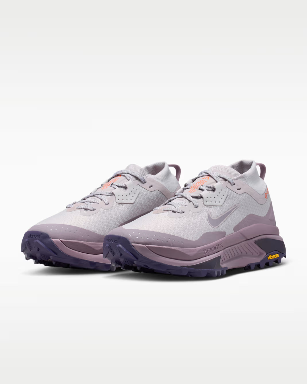A Nike ACG ZEGAMA ZOOMX trail running shoe in a light lavender and purple colorway, featuring a textured mesh upper, a purple Swoosh, and a purple Vibram outsole, shown from a side profile on a light gray background.