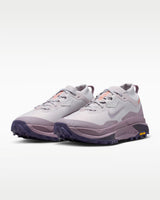 A Nike ACG ZEGAMA ZOOMX trail running shoe in a light lavender and purple colorway, featuring a textured mesh upper, a purple Swoosh, and a purple Vibram outsole, shown from a side profile on a light gray background.