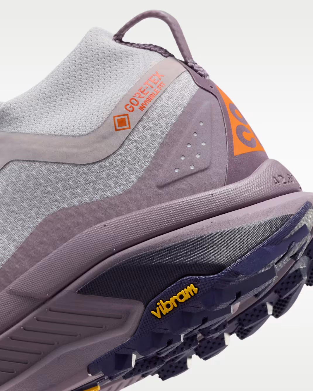 A Nike ACG ZEGAMA ZOOMX trail running shoe in a light lavender and purple colorway, featuring a textured mesh upper, a purple Swoosh, and a purple Vibram outsole, shown from a side profile on a light gray background.