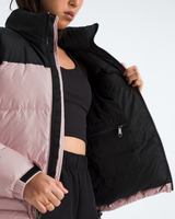 A close-up of a model wearing a color-blocked puffer jacket with a black exterior and light pink interior lining, shown open to display the inner zippered pocket.- The North Face 1996 Retro Nuptse Jacket (Womens) - Metal Pink/TNF Black