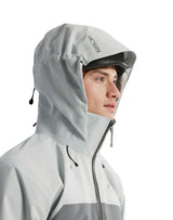 A close-up side profile of a model wearing an Arc'teryx light gray hooded rain jacket against a solid white background. - Arc'teryx Beta AR GORE-TEX Jacket (Men's) - Solitude/Void