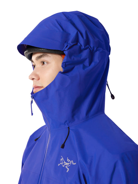 A close-up side profile of a person wearing a bright royal blue hooded rain jacket against a plain white background. The Arc'teryx bird logo is visible on the chest. - Arc'teryx Beta SL GORE-TEX Jacket (Men's) - Vitality II